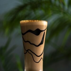 Tall glass of creamy chocolate shake with artistic swirls, perfect for refreshing indulgence.